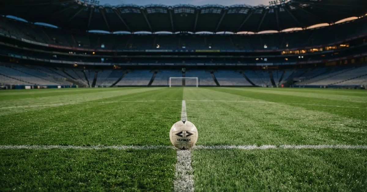 Piłka nożna leżąca na środku murawy w pustym stadionie przed meczem, rzędy siedzisk w półmroku.